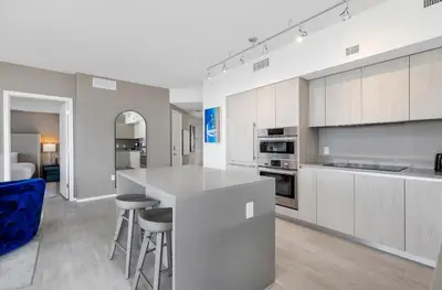 a kitchen with a white counter and stools in it at Hyde Beach House - Stunning 2bd 2ba - Apt - Ocean & Intercostal views in Hollywood