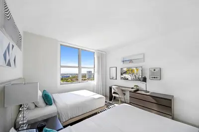 a bedroom with two beds and a desk and a window at Hyde Beach House - Stunning 2bd 2ba - Apt - Ocean & Intercostal views in Hollywood