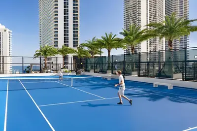 a couple of people playing tennis on a tennis court at Hyde Beach House - Stunning 2bd 2ba - Apt - Ocean & Intercostal views in Hollywood