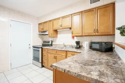 a kitchen with wooden cabinets and a counter top at Modern 3-Bedroom in the Heart of Wynwood Art District in Miami