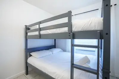 a bunk bed with white sheets and a ladder at Modern 3-Bedroom in the Heart of Wynwood Art District in Miami