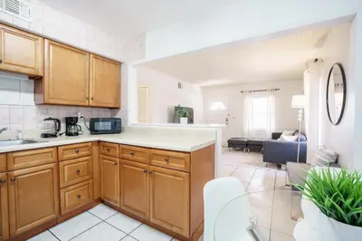 a kitchen with wooden cabinets and a living room at Modern 2 Bedroom in the Heart of Wynwood Art District in Miami
