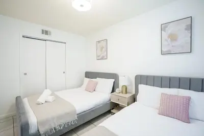 two beds in a bedroom with white and pink pillows at Modern 2 Bedroom in the Heart of Wynwood Art District in Miami