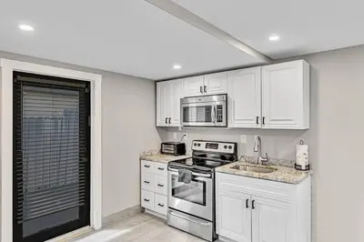a kitchen with white cabinets and a stove and microwave at Modern Villa with Pool Hollywood Hard Rock Casino in Fort Lauderdale