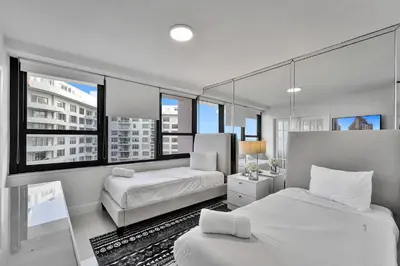 two beds in a room with large windows at Cozy Beachfront 2 BDR & 2 BA Miami Beach Condo in Miami Beach