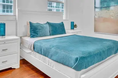 a white bedroom with a large bed with blue sheets at Ocean View Amazing Unit Brickell in Miami