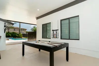 a ping pong table in a room with a swimming pool at The tropical paradise villa in Miami
