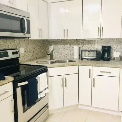 a kitchen with white cabinets and a sink and a microwave at LOCATION! Apartment in Coconut Grove with parking in Miami