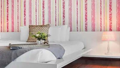 a bedroom with a white bed with a striped wallpaper at Oceanfront Private Penthouse Condo at The Setai -3909 in Miami Beach