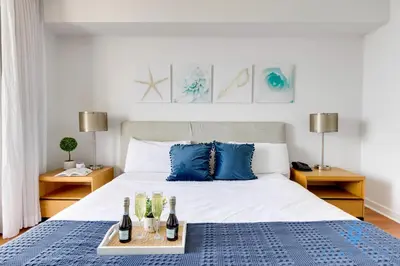 a bedroom with a large bed with blue pillows at Apartment with Balcony, Gym, Pool in Hallandale Beach