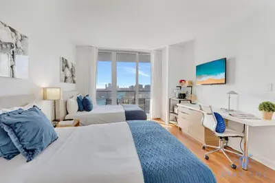 a white bedroom with a desk and a bed at Apartment with Balcony, Gym, Pool in Hallandale Beach
