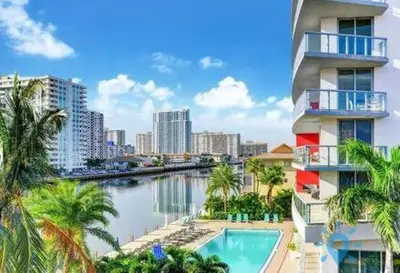 a building with a swimming pool next to a river at Apartment with Balcony, Gym, Pool in Hallandale Beach