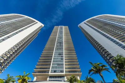 two tall buildings against a blue sky with palm trees at The Ultimate Resort - BEACHFRONT 2 BEDROOM APARTMENT WITH DIRECT OCEAN VIEW, ROOFTOP POOL, HOT TUB AND GYM in Hollywood
