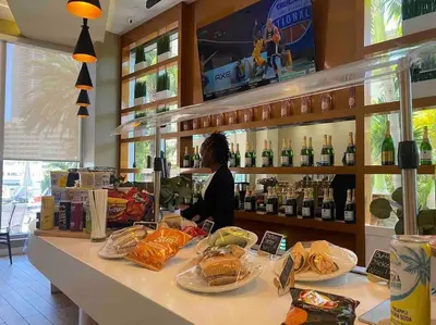 a woman sitting at a counter in a restaurant with food at Dream Beach Apt 1BR Kitchen & Pool Access 06A in Hallandale Beach