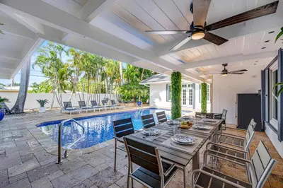 a patio with a table and chairs and a pool at Private neighborhood Heated Pool Walk To Beach Lush Surroundings Harbor Key in Fort Lauderdale