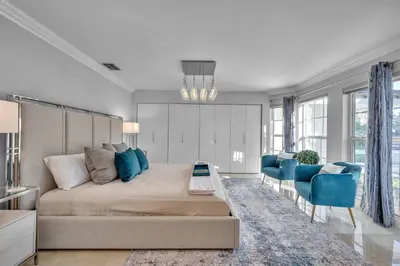 a bedroom with a large bed and blue chairs at Waterfront Villa Walk to Beach Venice of America Coastal Extravagance Palm Key VlLLAS in Fort Lauderdale