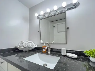 a bathroom with a white sink and a mirror at Bella Vista - Water views Pool and Parking in Miami Beach