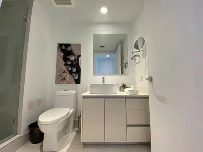 a bathroom with a toilet and a sink and a mirror at Modern Beach Apartment, 3 Beds, Views & Full Kitchen in Hallandale Beach