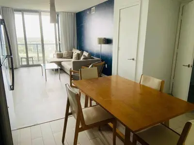 a living room with a table and a couch at Modern Beach Apartment, 3 Beds, Views & Full Kitchen in Hallandale Beach