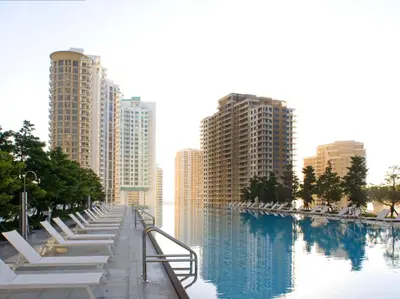 a row of white lounge chairs next to a body of water at Wonderful 2 BR Condo Icon Brickell With Pool in Miami