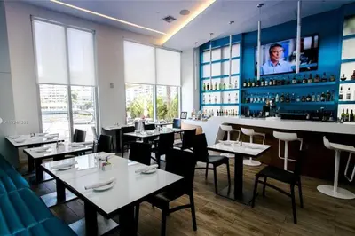 a restaurant with tables and chairs and a bar at Chic Coastal Apartment, Views, Comfort & Full Kitchen -A in Hallandale Beach
