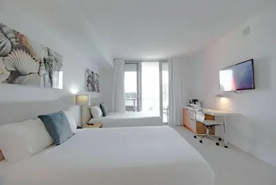 a white bedroom with a large bed and a desk at Just Minutes from the Beach, 2 Full Bed Studio in Hallandale Beach
