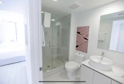 a white bathroom with a toilet and a sink at Just Minutes from the Beach, 2 Full Bed Studio in Hallandale Beach