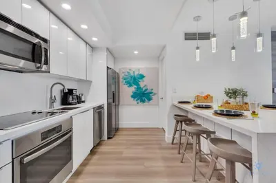 a kitchen with white cabinets and bar stools at Modern Resort with Balcony - Pool - Gym in Hallandale Beach