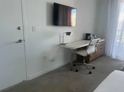a bedroom with a desk with a chair and a television at Your Coastal Studio, 2 Full Beds & Ocean Vibes in Hallandale Beach
