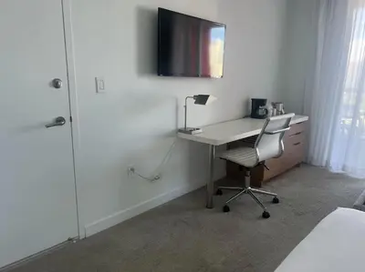 a bedroom with a desk with a chair and a television at Stylish BeachWalk Studio, Sleep 4 Comfortably in Hallandale Beach