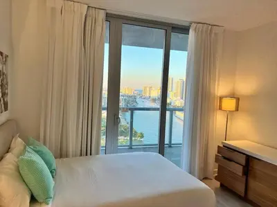 a bedroom with a bed and a large window at Walk to the Waves, 2 Full Bed Beach Studio Stay in Hallandale Beach