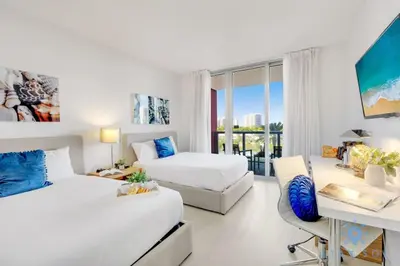 a hotel room with two beds and a desk and a desk at Pool - Apartment with Balcony - Gym - Near Beach in Hallandale Beach