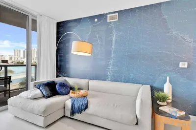 a living room with a couch and a blue wall at Pool - Apartment with Balcony - Gym - Near Beach in Hallandale Beach